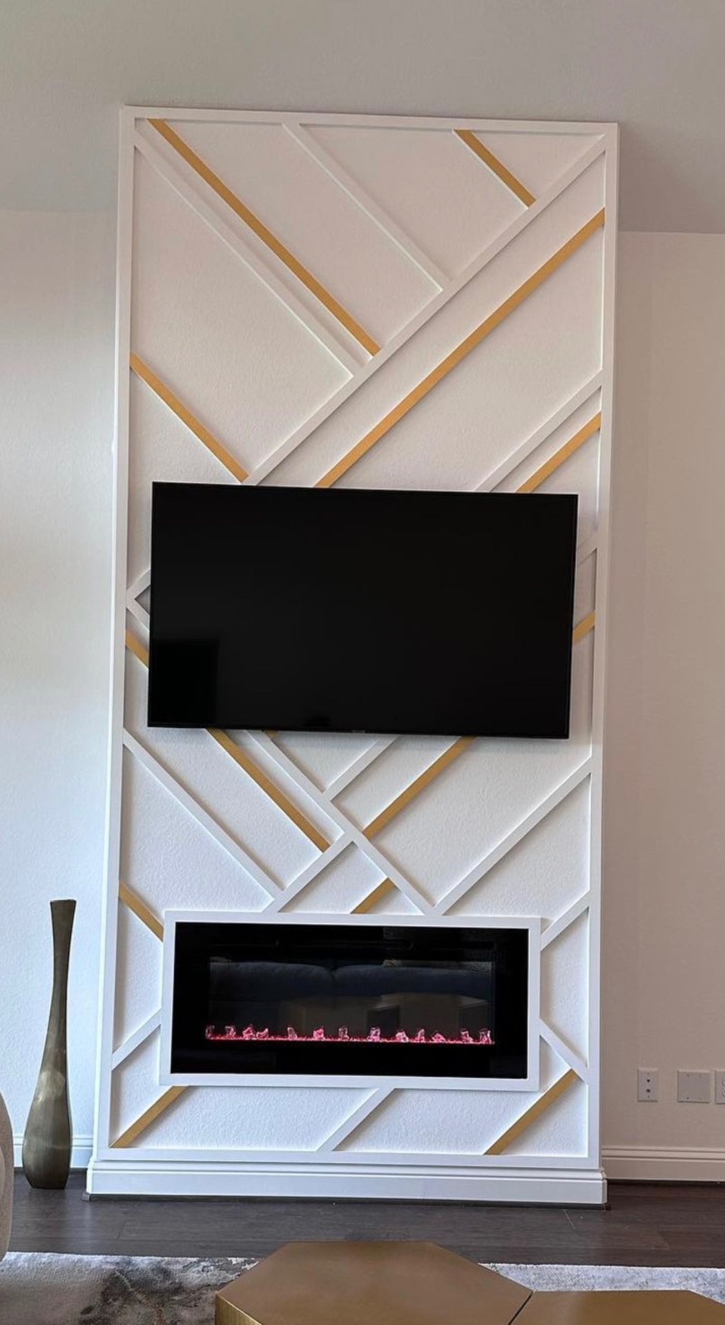 White + gold geometric accent wall with fireplace & TV